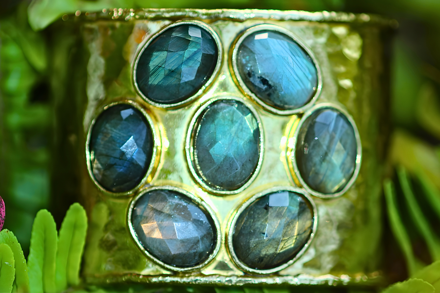 Gold bracelet with blue gemstones on a green leafy background