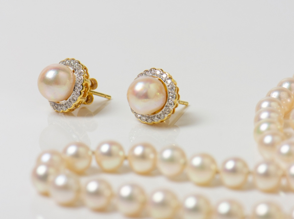 a pair of white pearl earrings and pearl necklace.